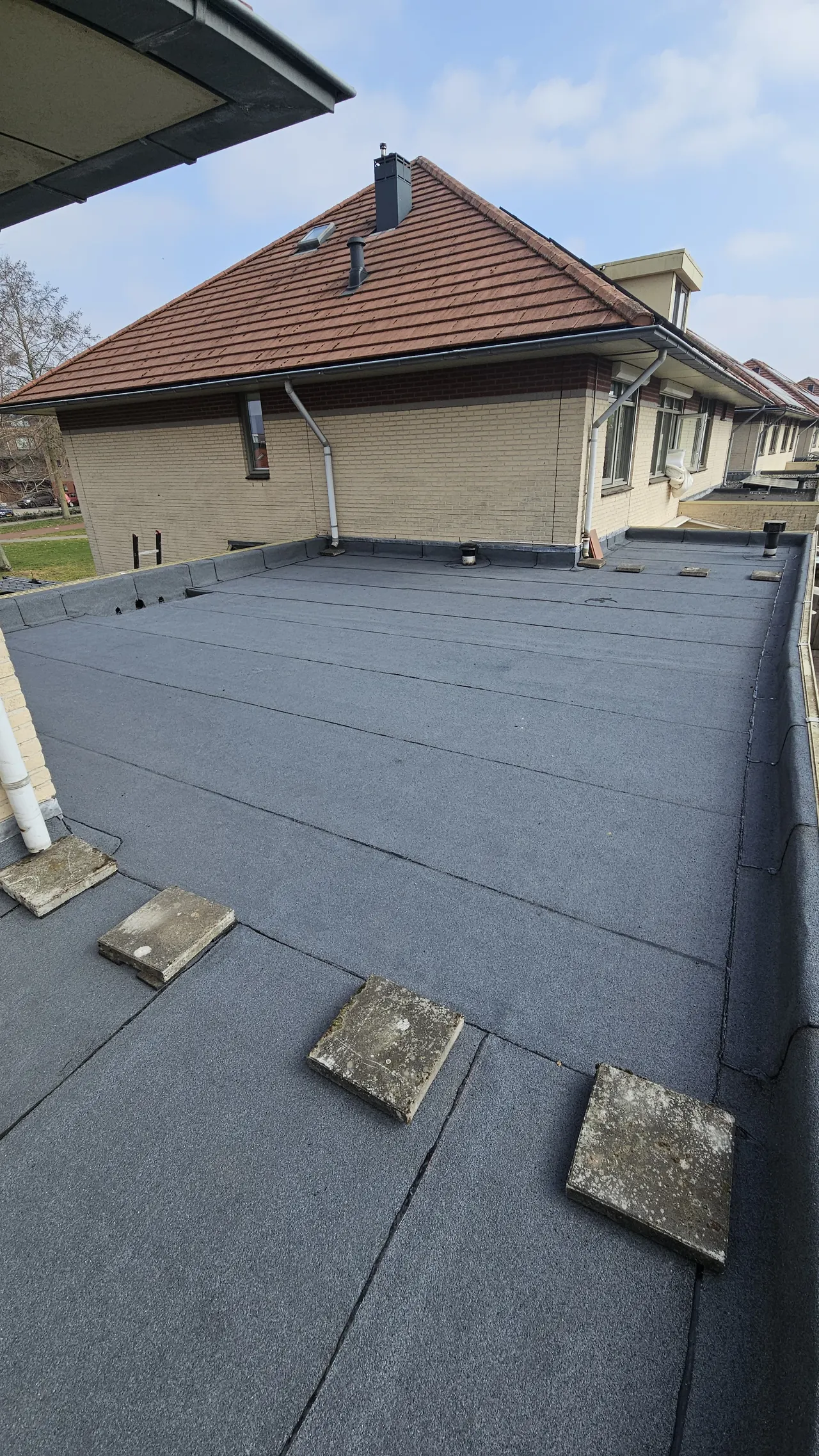 Bitumen dakbedekking op garage en uitbouw naast een woning in Harderwijk