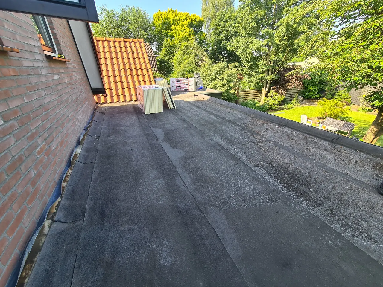 Dak van een overkapping langs een gevel tijdens renovatie in Apeldoorn